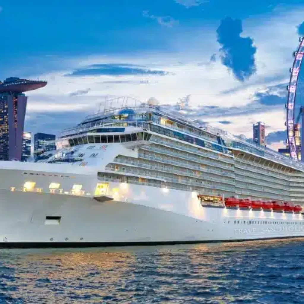 A cruise ship docked in Singapore with the city skyline in the background.